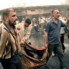 Ciudadanos iraquíes trasladan en una sábana los restos mortales de una de las víctimas del atentado