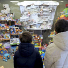 Dos niños observan el interior de una tienda de juguetes.