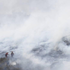 Una brigada contra incendios trabaja en medio de un denso humo en uno de los frentes del incendio de La Cabrera.