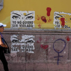 Una mujer pasa por una calle con carteles contra la violencia sexual. GUSTAVO AMADOR