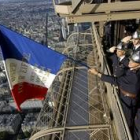Bomberos de París cuelgan la bandera nacional de la torre Eiffel durante la celebración de ayer