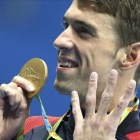 Phelps muestra su medalla señalando los cuatro oros que ha conseguido hasta ahora.