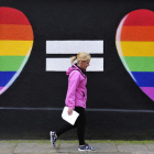 Una mujer camina junto a una pintada de dos corazones con los colores del arcoíris en Dublín.