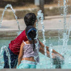 Un niño y una niña se mojan en una fuente en Menorca. DAVID ARQUIMBAU SINTES