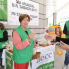 Una voluntaria de la Asociación Contra el Cáncer ofrece fruta a cambio de un cigarro.