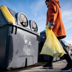 Una mujer recicla envases de plástico en el contenedor amarillo.