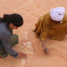 La arqueóloga ponferradina Mireya González escarba en la arena del desierto junto a un nativo, en un imagen tomada en las dunas del suroeste de Libia y anterior a la revuelta popular contra el sátrapa Muamar el Gadafi.