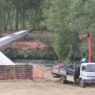 Los operarios trabajan en la colocación de la pasarela sobre el río Porma.