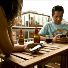 Una pareja de turistas consulta sus móviles en una terraza de Barcelona.