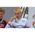 Leonard Kamna, con el maillot arcoiris de campeón del mundo, muerde en el podio su medalla de oro junto al norteamericano Costa y el australiano Storer.
