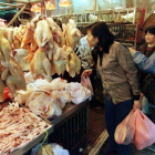 Mujeres chinas compran pollo en un mercado.