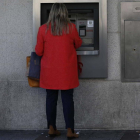 Una mujer ante un cajero de banco.