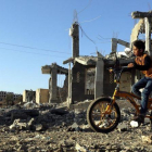 Un niño yemení pasea con su bicicleta junto a los escombros de una vivenda en Saná destrozada por los bombardeos aéreos.