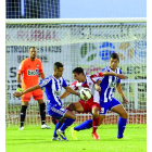 Acorán y Néstor se llevan un balón ante el rojiblanco Marquitos.