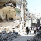 Vecinos de Alepo pasan junto a un edificio destruido en un bombardeo del régimen, este domingo.