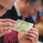 Un periodista inspecciona un nuevo billete de 200 euros.