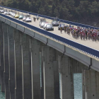 El pelotón, con todos los coches de avituallamiento y apoyo detrás, a su paso por el puente sobre el embalse de Riaño.