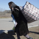 Una mujer ucraniana camina por la carretera con sus pertenencias en una bolsa. AMEL PAIN