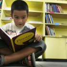 Un niño lee un cuento en una biblioteca.