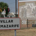 Cartel anunciador de la localidad de Villar de Mazarife, con la pista de futbito al fondo