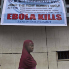 Una mujer pasa bajo un anuncio de alerta sobre el virus del Ébola en Freetown (Sierra Leona).