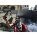 Un opositor a Mursi muestra una pistola hallada en la sede incendiada de los Hermanos Musulmanes, este lunes en El Cairo.