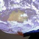 Un participante en la cumbre del clima posa ante la bola del mundo que se exhibe en el encuentro