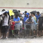 Un grupo de personas hace cola bajo una intensa lluvia en una tienda de ultramarinos en Carolina del Norte.