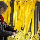 Una mujer coloca lazos amarillos en una verja