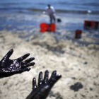 Voluntarios cargan cubos de petróleo de las costas de Santa Bárbara.