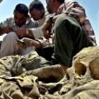 Varios iraquíes analizan la documentación de unos restos humanos hallados en una fosa común de Irak