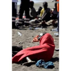 Unos inmigrantes descansan arropados en la playa de El Confital