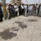 Varios iraquíes observan los restos de sangre en el lugar donde explosionó la bomba