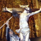 Una operaria limpia el polvo a un Cristo que se expone en la iglesia de Santiago de los Caballeros.