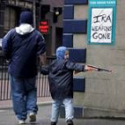 Un niño para frente a tablón de edictos en el centro de Belfast que pide el desarme del IRA