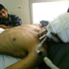 Un iraquí sostiene la mano de su hermano, herido de gravedad en el atentado contra la base de Tayi