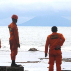 Miembros de los servicios de rescate observan la actividad del volcán Anak Krakatau desde la playa indonesia de Carita.