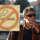 Un hombre fuma un cigarrillo en el exterior de un bar