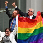 Tres diputados agitan la bandera arcoiris tras la aprobación de la ley.