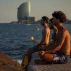 Tres jóvenes practican yoga al atardecer y frente al mar en el popular espigón del Gas de Barcelona. ENRIC FONTCUBERTA