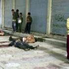 Un grupo de niños mira en Ramadi los cuerpos de varios iraquíes asesinados por los rebeldes