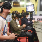 Unos adolescentes juegan a videojuegos en 3D en una feria de Barcelona. /