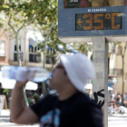 Un hombre bebe agua ante un termómetro que marca los 35 grados, en una imagen de archivo.