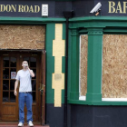 Un cliente bebe a las puertas de un bar con las ventanas protegidas en el barrio londinense de Croydon.