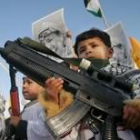 Varios niños palestinos recorren las calles con armas de juguete contra del muro