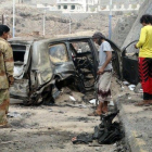 Varias personas contemplan los efectos del atentado con coche bomba en el que ha muerto el gobernador de Aden.