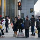 Varias personas en una calle muy transitada de Beijing.