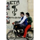 Unos jóvenes conducen una moto delante de una pintada de ETA
