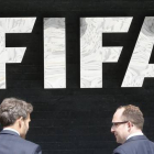Dos hombres pasan por delante de la sede central de la FIFA en Zúrich.