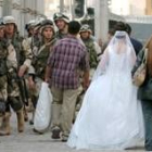 Soldados de la coalición contemplan el paso de una novia por una calle de Bagdad